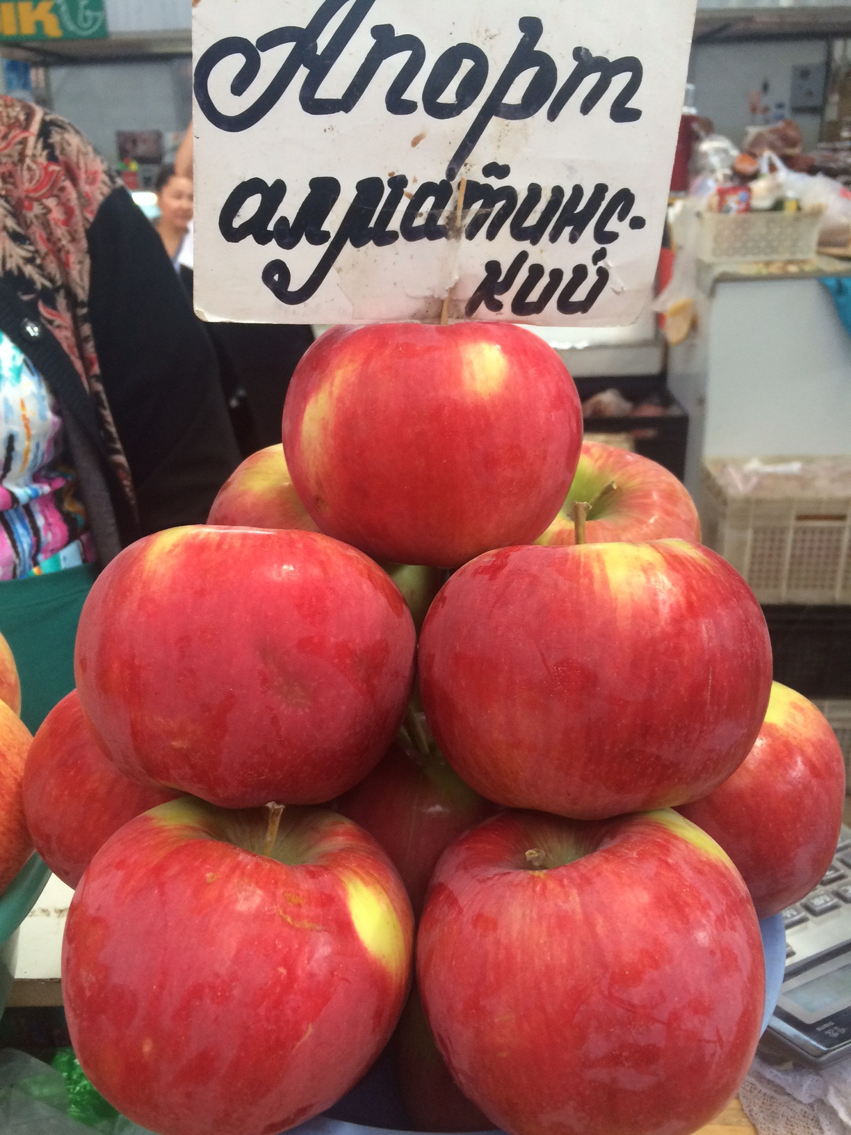 Пирамида красных крупных яблок Апорт на прилавке рынка с табличкой «Апорт алма-атинский»